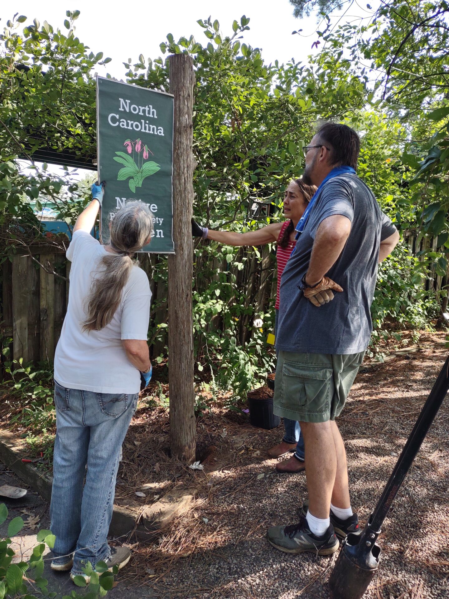 Several people installing a Native Plant sign